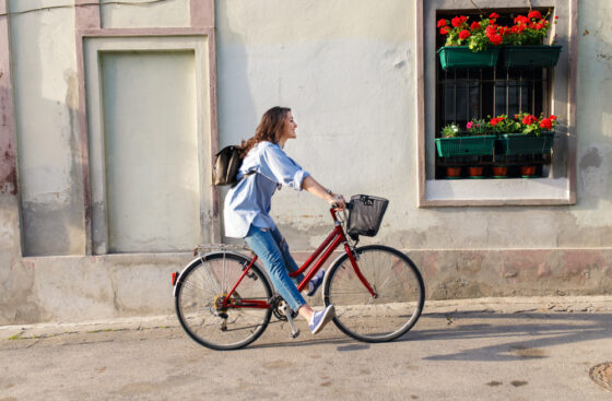 Young,Woman,Riding,A,Bicycle,Down,The,Street.